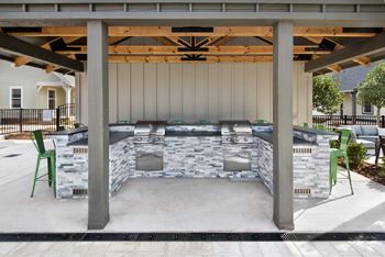 A covered patio with a barbecue grill and chairs